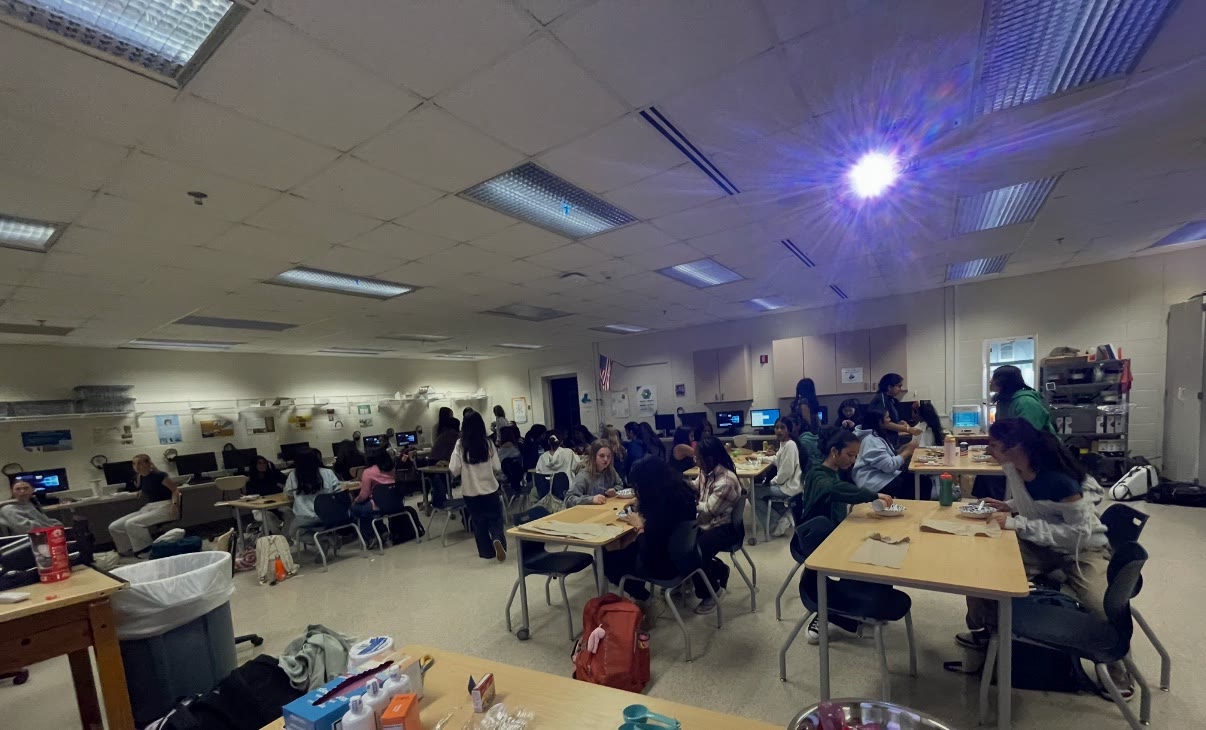 A classroom full of students working at tables during a Girls in STEM meeting